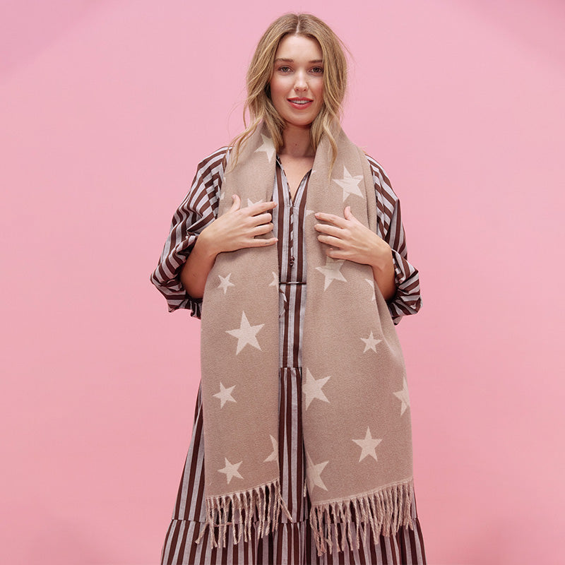 Woman wearing a beige scarf with star patterns on a pink background