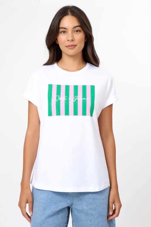 A woman modeling a white short-sleeve t-shirt with a green striped graphic on the chest, paired with light blue denim shorts, against a plain white studio background.