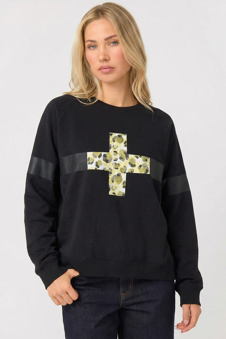 Woman wearing a black sweater with a floral cross design on a white background