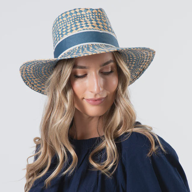 Woman wearing a blue and white patterned sun hat against a plain background