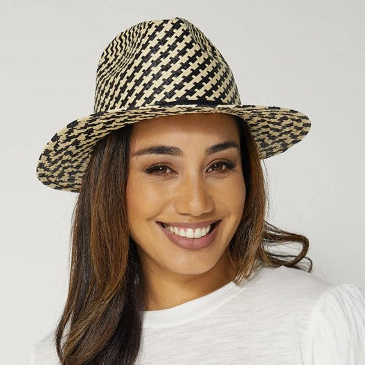 Woman wearing a straw hat and white t-shirt against a plain background