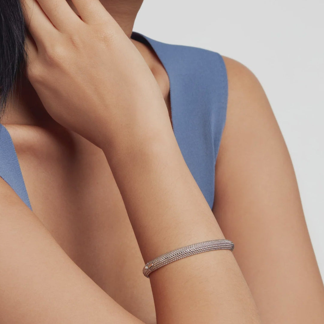 Woman wearing a SILVER TED BAKER bracelet on a plain background