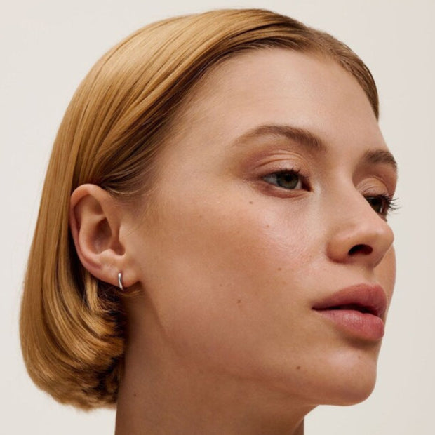 Close-up of a person with short blonde hair against a plain background WEARING SILVER TED BAKER EARRINGS