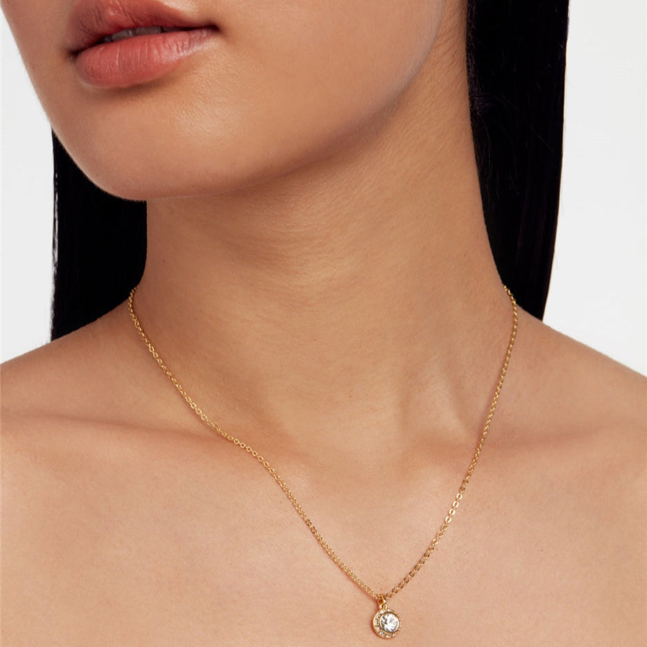 gold TED BAKER necklace with a small pendant on a model against a white background