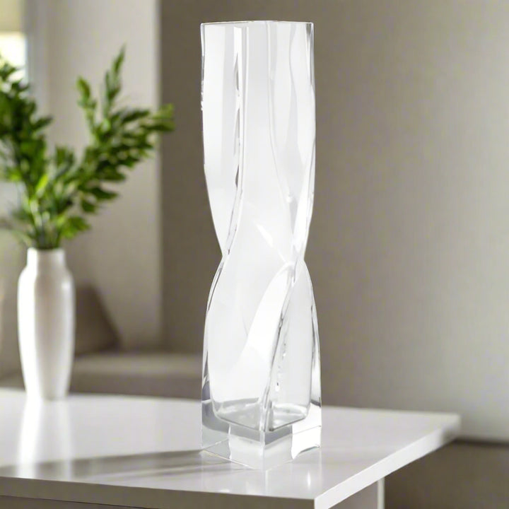 Clear glass vase with a twisted design on a white background