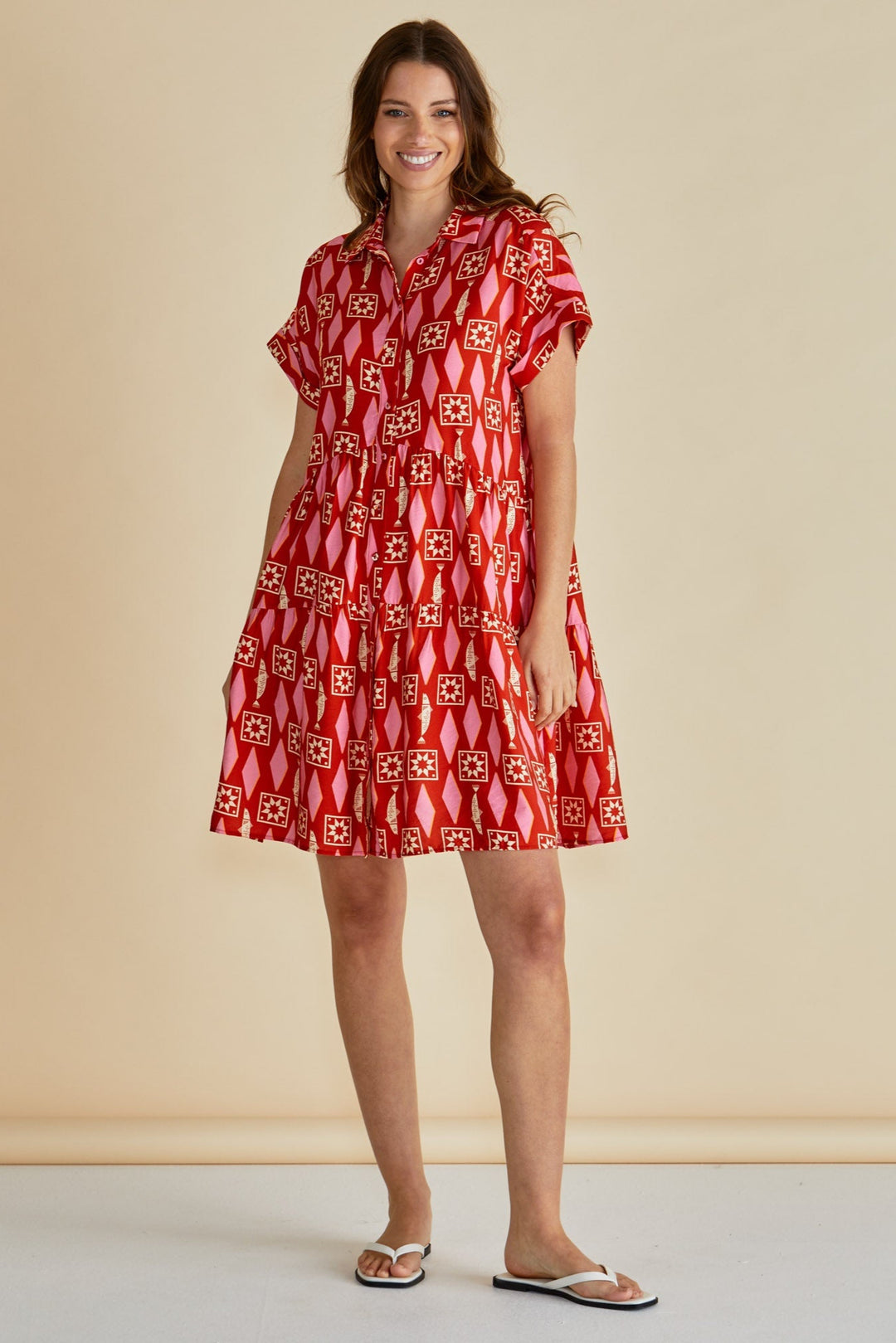 Woman wearing a red patterned betty basics dress against a beige background