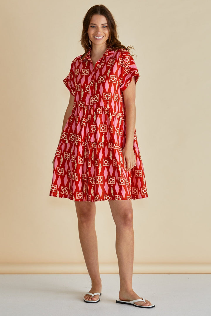 Woman wearing a red patterned betty basics dress against a beige background