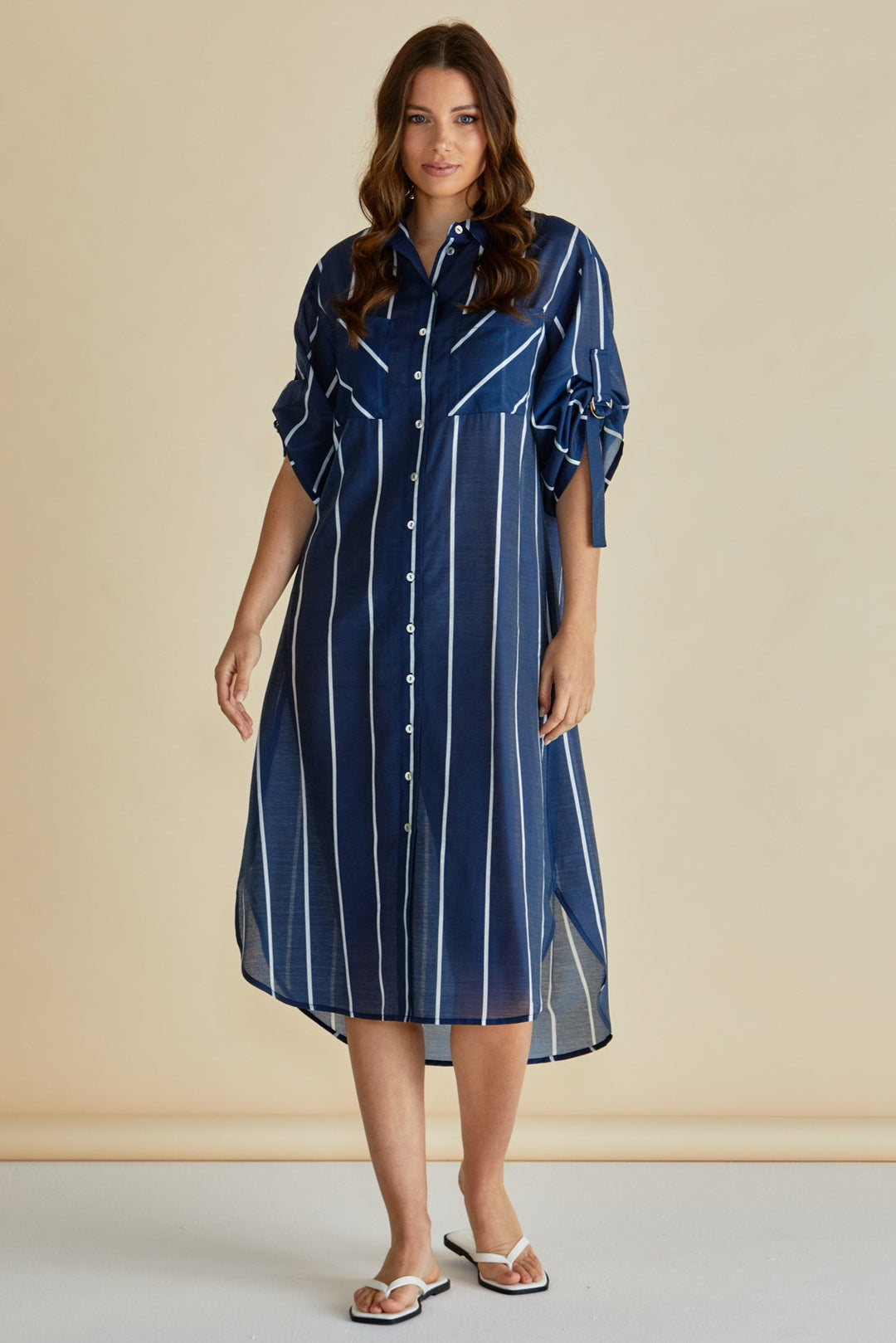 Woman wearing a blue striped betty basics dress against a beige background