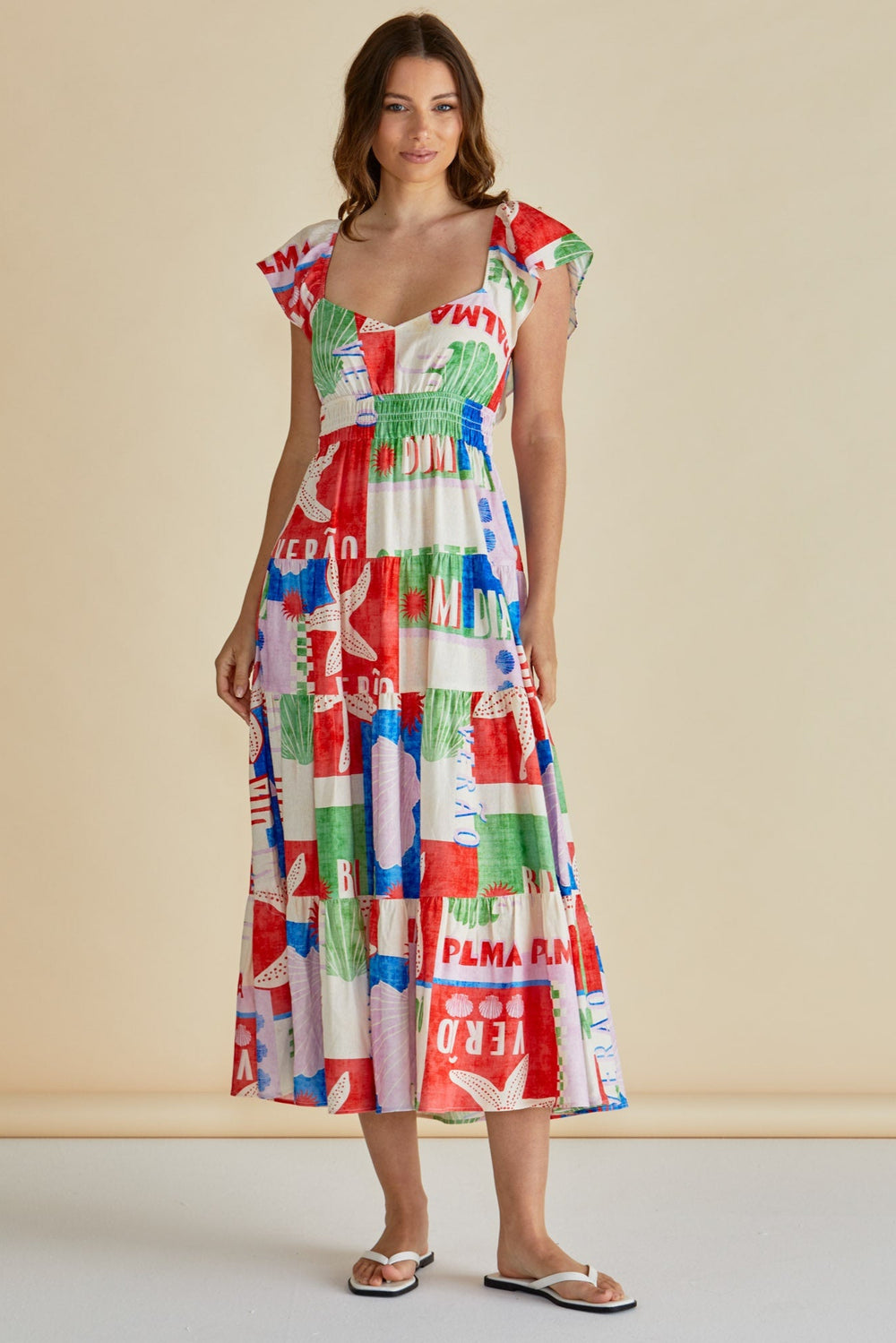 Woman wearing a colorful BETTY BASICS SUMMER dress with a pattern on a beige background