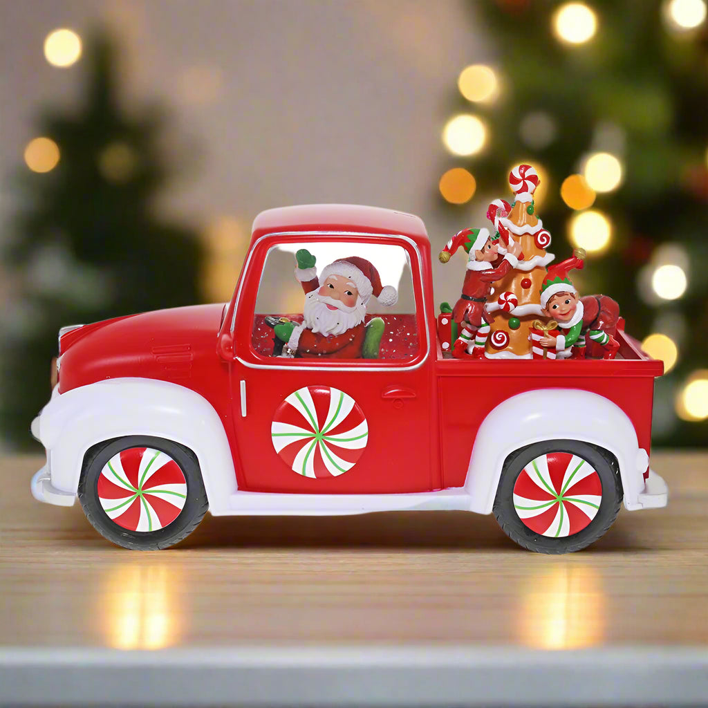 Red Christmas truck with Santa Claus figure and candy-themed decorations on a white background