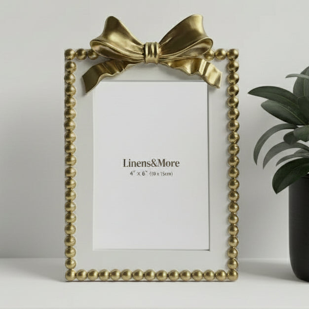Gold picture frame with a bow on a white background