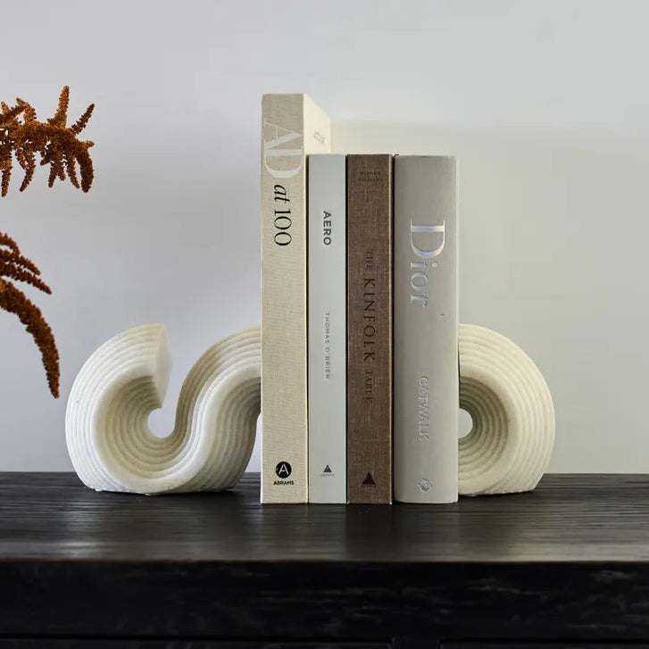 set of stylish white s shaped bookends with books on a dark sideboard cabinet