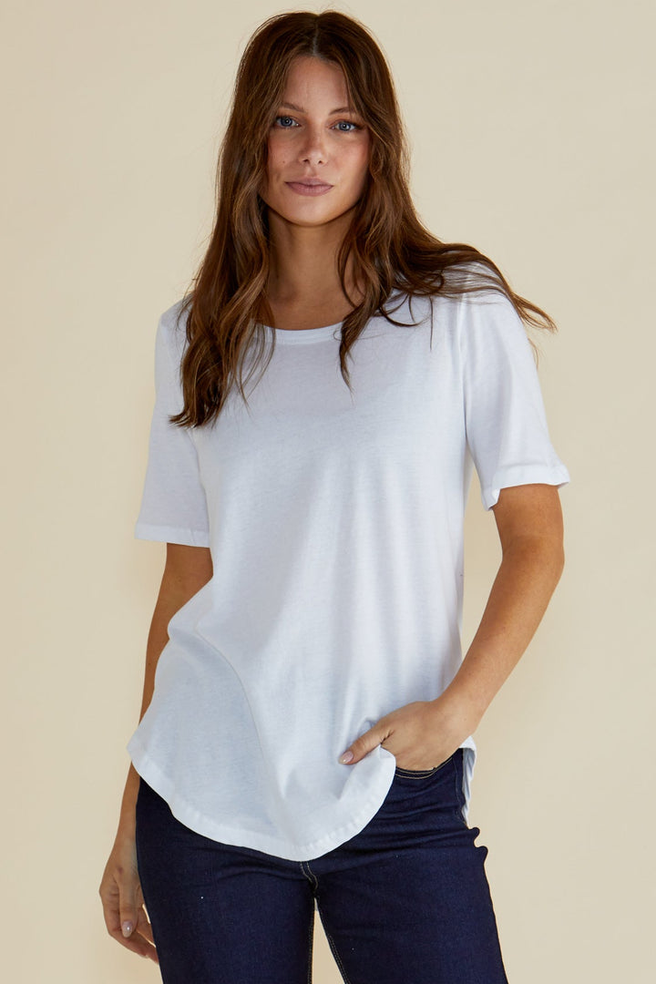 Woman wearing a white t-shirt and dark jeans on a beige background