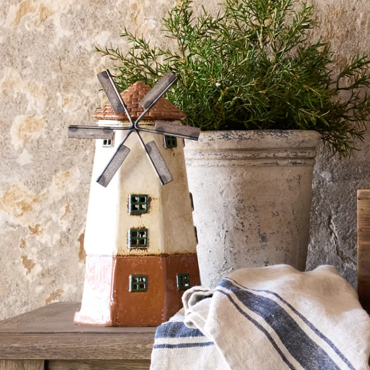 Decorative windmill with a plant and striped towel on a stone surface