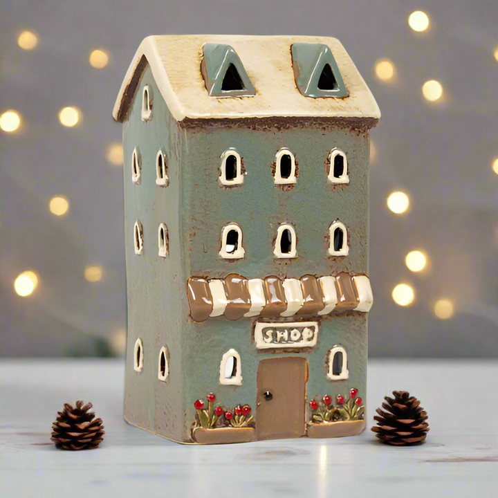 Small ceramic house with a 'Shop' sign on a white background