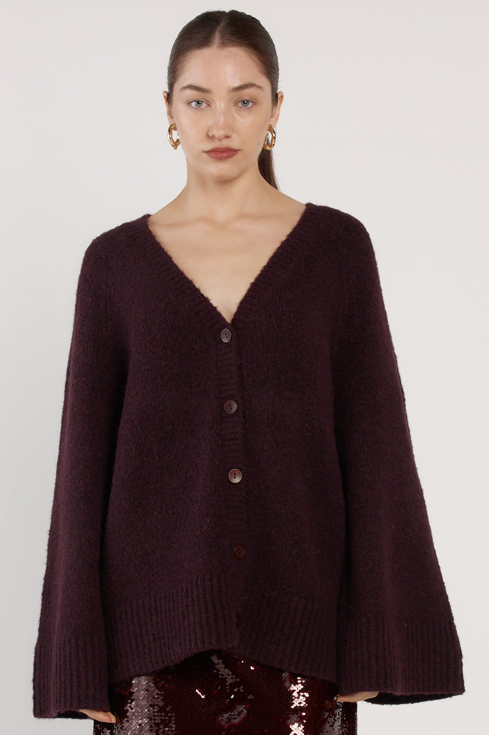 Woman wearing a dark brown sweater with a plain background