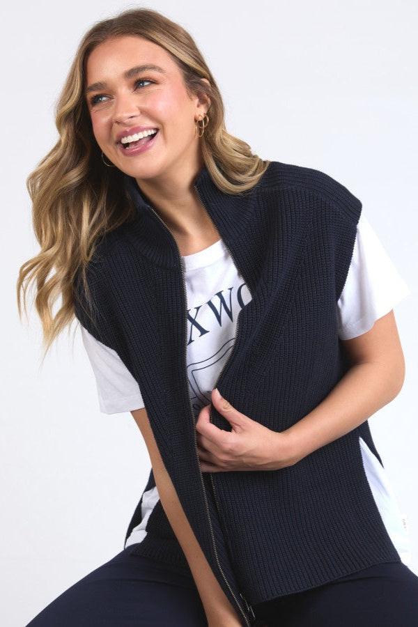 Woman wearing a navy vest over a white t-shirt with text on a plain background